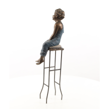 Sculpture en polystone d'un petit garçon sur une chaise